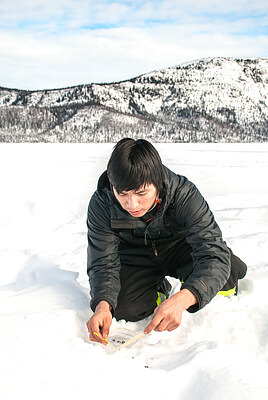 Charles Oudzi collects caribou scat on Tets’ehxe (Drum Lake) in the Shúhtagot’ı̨nę Nę́nę́ (Mackenzie Mountains) of the Northwest Territories, Canada. Caribou scat, collected non-invasively, provides genetic information that is used to analyze the connectivity and relationships between different caribou populations in the region. The research is dependent on the voluntary collection of scat samples by local hunters and trappers. Credit&#58; Jean Polfus